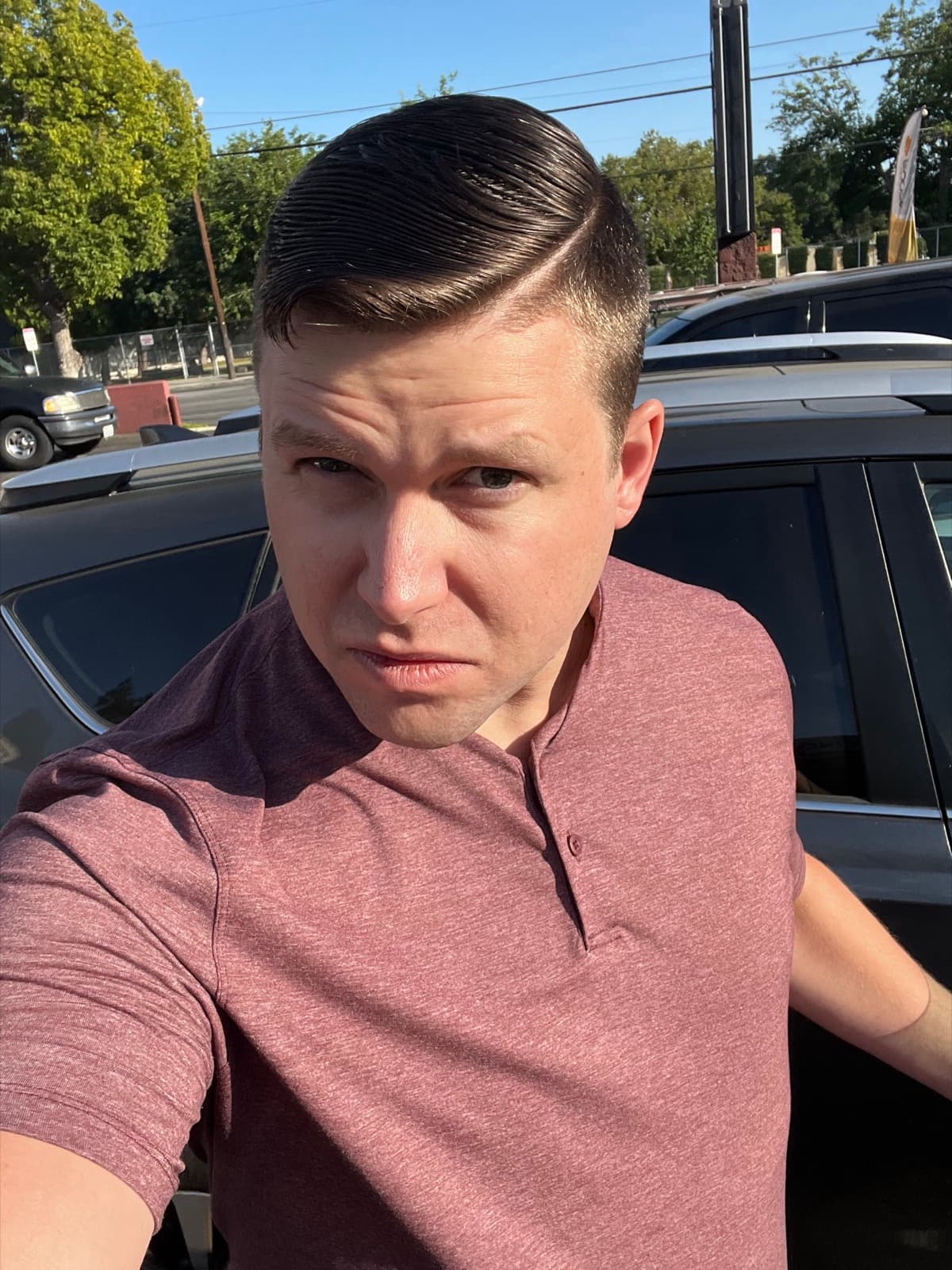 Jeremy Gulley in a maroon polo shirt, standing outdoors beside a car